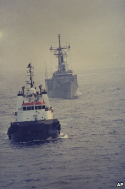 یک کشتی مین‌روب کویتی، پس از برخورد ناو ساموئل رابرت با مین، در حال انتقال آن به دوبی است.
